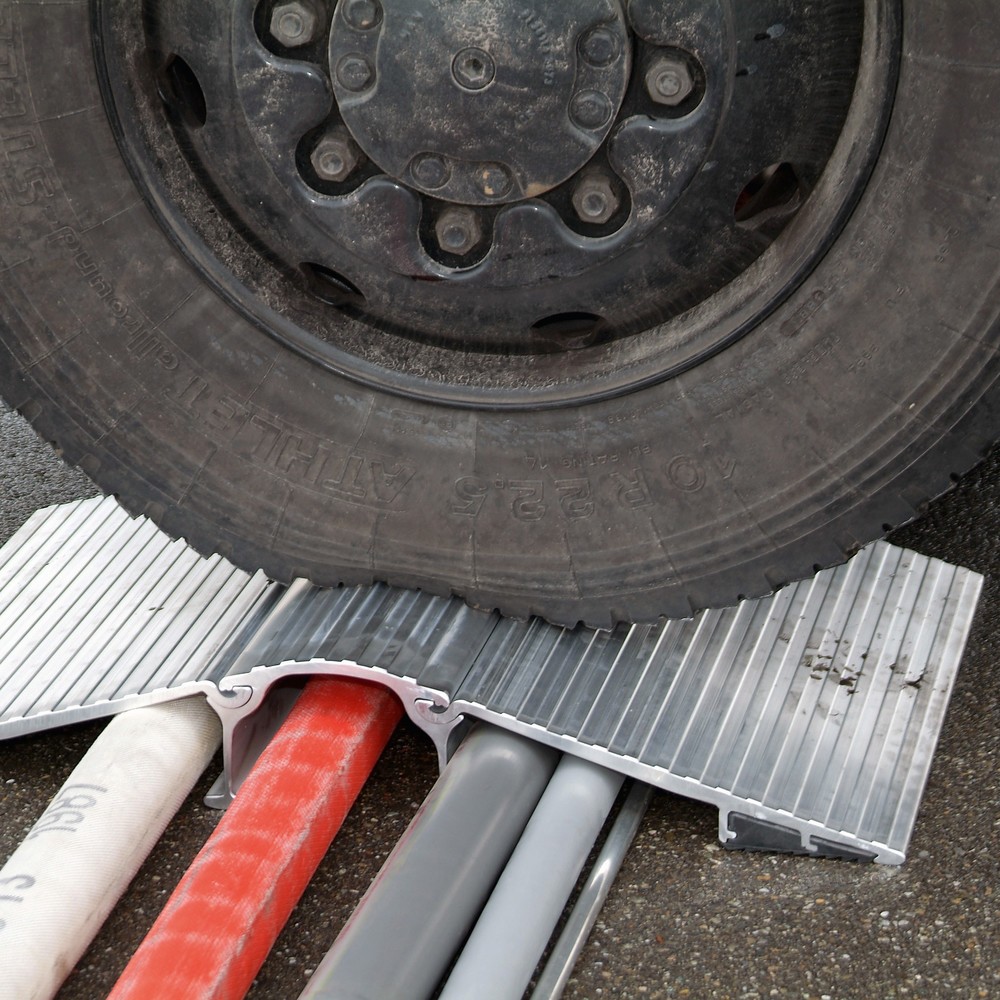 Autoreifen auf einer Aluminium-Überfahrbrücke über Leitungen