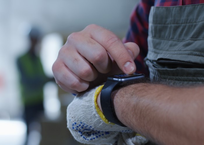 Mann benutzt Pick-by-Watch-Verfahren zur Kommissionierung im Lager